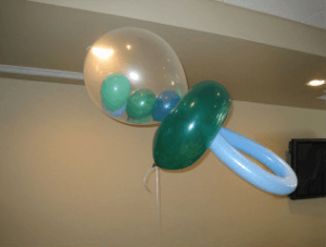 Balloons arranged to resemble a baby pacifier, with smaller balloons inside a large transparent balloon.